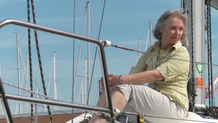 Happy mature woman sitting on a sail boat as it passes, on the Puget Sound in