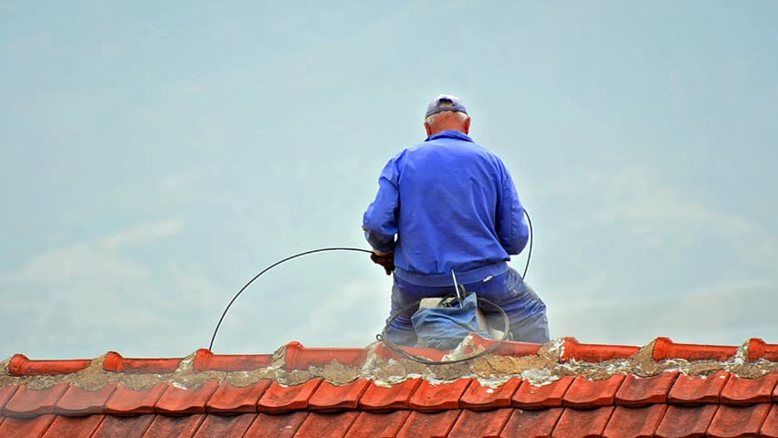 Chimney sweep. Sweeper working on a roof sitting on edge.