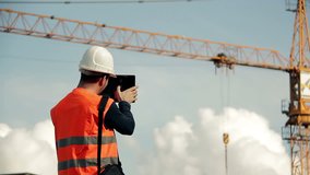 Construction engineer wearing safety vest with yellow crane on the background us - Powered by Shutterstock - Get 15% off with code: PIKWIZARD15