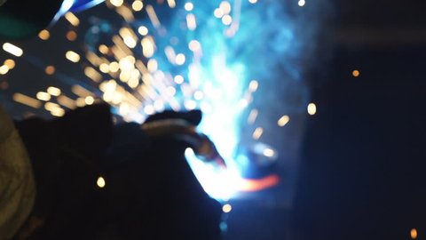 Workers grinding and welding in a factory. Welding on an industrial plant. Slow motion.