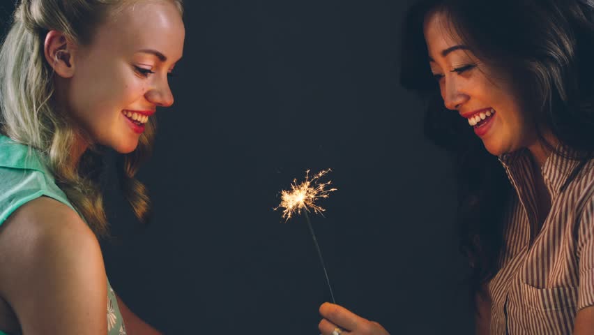 Young women celebrating holding sparkler cinemagraph seamless loop