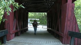Man with guitar in covered bridge playing folk and country music. Learning to play guitar to produce a homemade music video. 
