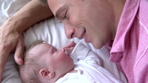 Young father kisses sleeping infant daughter on the forehead in slow motion