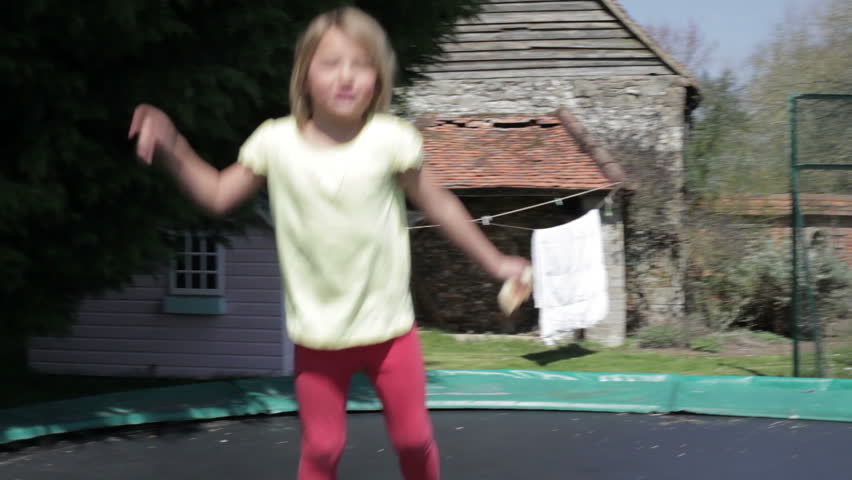 Happy young girl jumping on outdoor trampoline