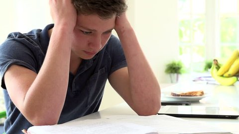 Portrait of stressed teenage boy stressed overwhelmed by homework slow motion