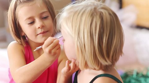 Two young girl play make up together and put eye shadow on each other