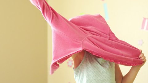 A young girl gets dressed and puts her sweatshirt on to start the day