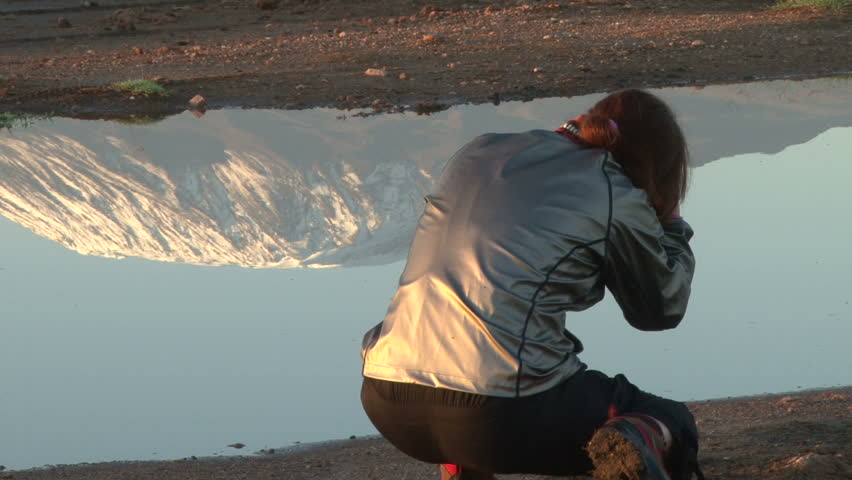 a lady photographer trying to capture the reflection of kilimanjaro

