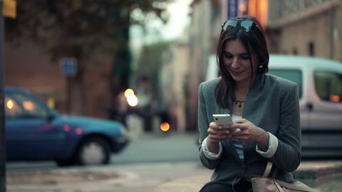 Elegant beautiful woman texting on smartphone in the city
