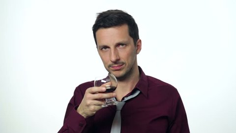 Man in business attire drinking too much alcohol. Studio setting on a white background. High definition video.