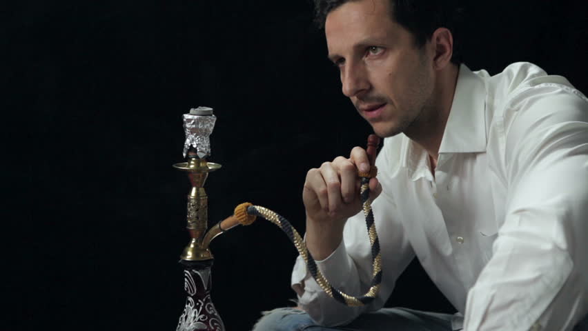 Man smoking a water pipe on black background. High definition video.