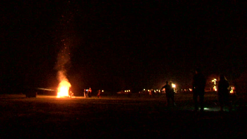 Family walk towards large fire burning at night.