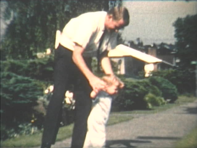 1960s vintage, archival home video of father helping toddler son learn to walk in Seattle, Washington neighborhood. Royalty-Free Stock Footage #4929260