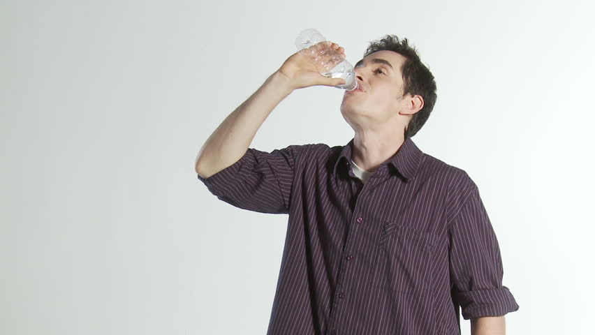 Young man takes a refreshing drink of water then walks out of frame.