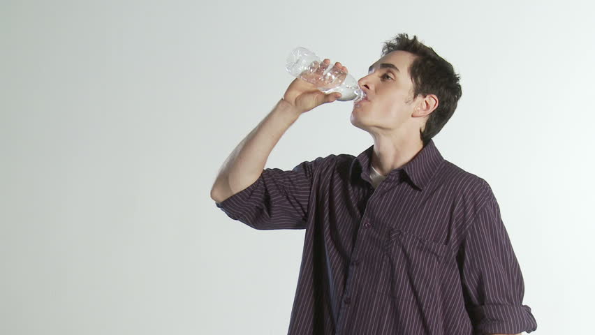 Young man walks into frame, takes a refreshing drink of water then walks out of