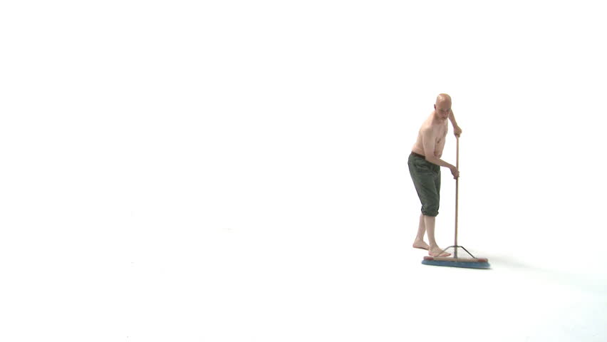 Bald man wearing long pants and no shirt sweeps up in a totally white space.