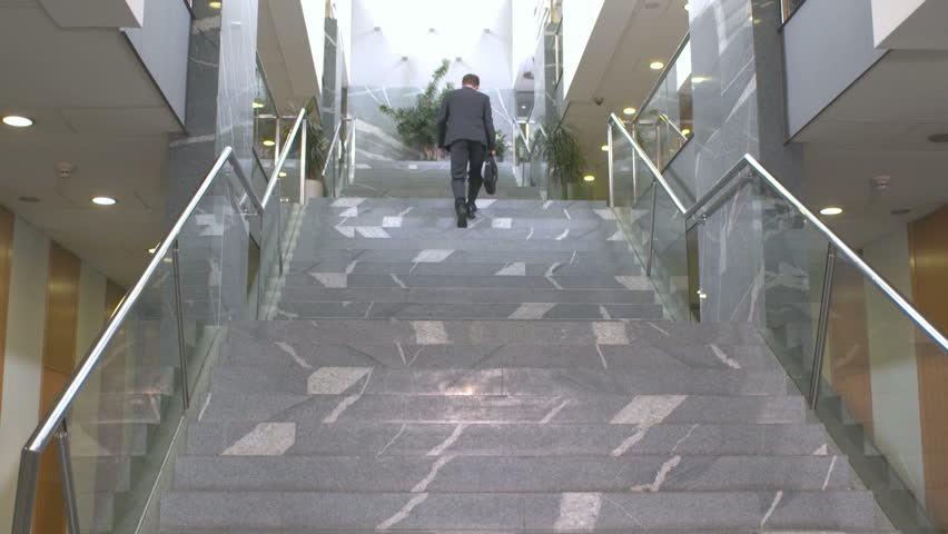 Edited Shot Of A Successful Businessman Walking Up The Stairs Inside Business