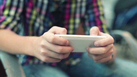Young teenager playing game on smartphone
