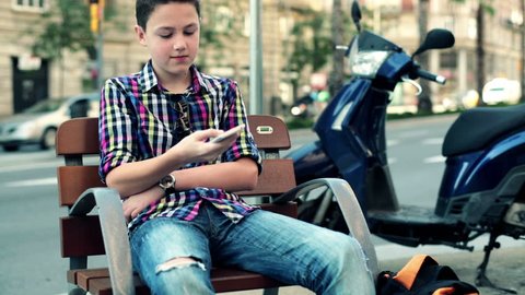 Teenager writing sms, texting on smartphone in the city

