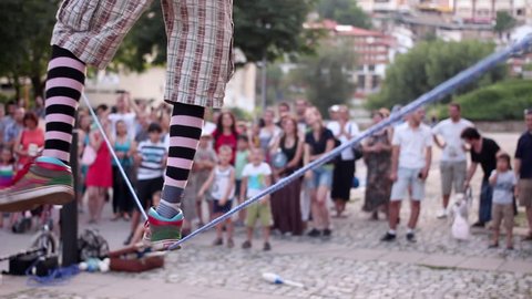 Street artist entertains the crowd during a street art festival. Walking a tightrope