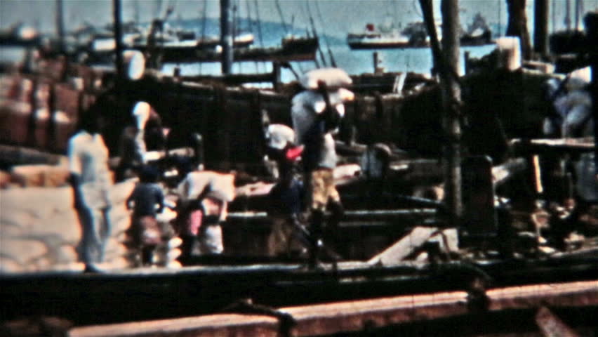 BANGKOK THAILAND CIRCA 1960: Historical vintage one of a kind film of unloading cargo ship in harbor. Men carry cargo off boat on back and shoulders. Once known as Siam. Boat ship harbor dock.