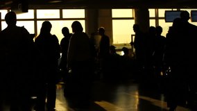 A sequence of silhouette clips of airport travelers walking by, waiting in line, and sitting in seats.