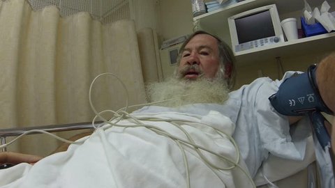 Man with big beard hospital recovery bed surgery HD. Mature man laying in recovery bed at ER emergency same day surgery hospital. Post medical procedure waking up after anesthesia.