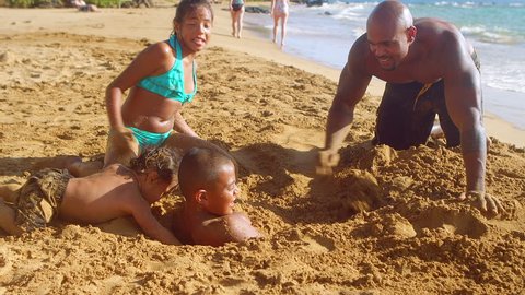 A family buries their brother in the sand at the beach