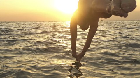SLOW MOTION: Woman jumping into the sea at sunset