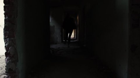 Horror scene, masked killer with machete chasing a girl in abandoned building through the hallways.