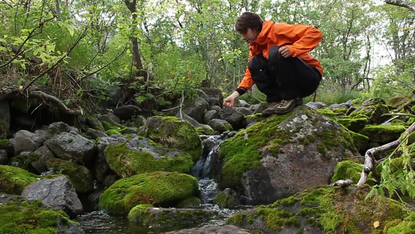 girl in the woods drinking water from a picturesque creek, washes up and go away, Russia, Hibiny mountain, august 2013