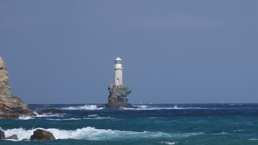 Lighthouse on the rock in stormy sea under waves
