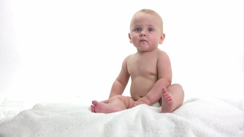 Baby sitting on a white towel playing, isolated on white background