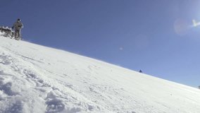 Slow Motion Of Skier Skiing Down The Snowy Slope. Clear Blue Sky And Sun Flares In The Background. 