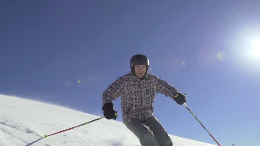 Slow Motion Of Skier Skiing Down The Snowy Slope. Clear Blue Sky And Sun Flares
