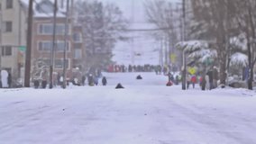 Three clips of time lapse of people sledding down hill in Seattle.