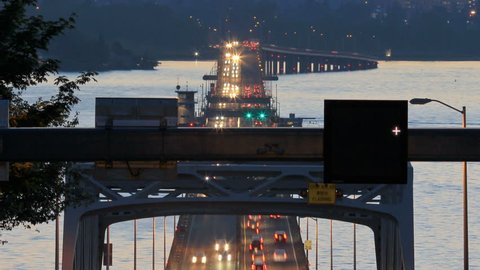 Panning clip of Seattle highway 520 traffic time lapse right after sunset with cars coming and going over bridge part and Olympic Mountains in background.