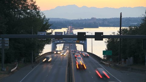 Seattle highway 520 traffic time lapse right after sunset with cars coming and going over bridge part and Olympic Mountains in background.