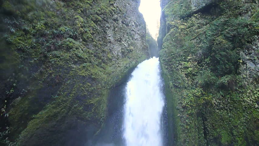 Camera tilt down on large waterfall in Oregon forest.