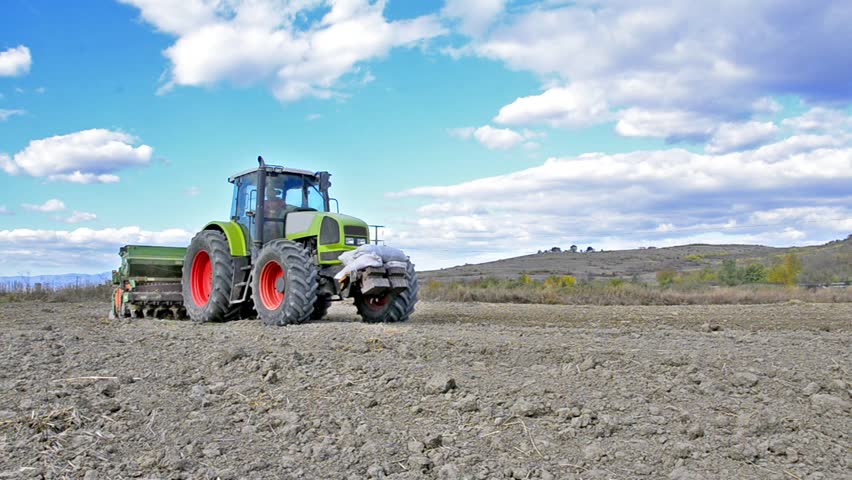 Agricultural tractor farming the land - Stock Video. Tractor on farmland, camera