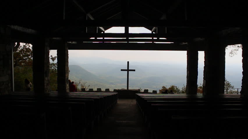 A silhouette of a cross that overlooks a beautiful mountain range