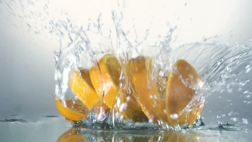 Orange slices splashing into water, slow motion