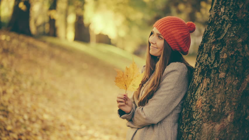 Girl in Autumn playing with Leaf in Park with vintage color correction