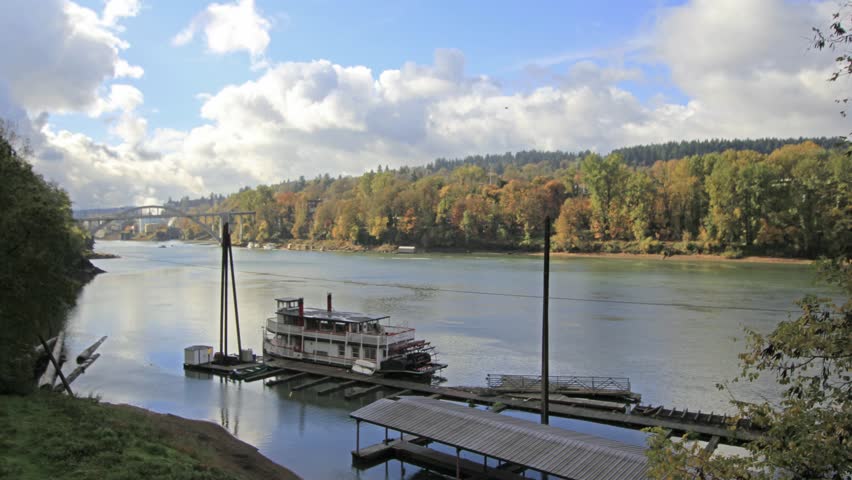Historic Sternwheeler Docked Along Willamette River in Oregon City in Fall Season with Moving White Clouds Blue Sky and Water Reflection Time Lapse 1920x1080