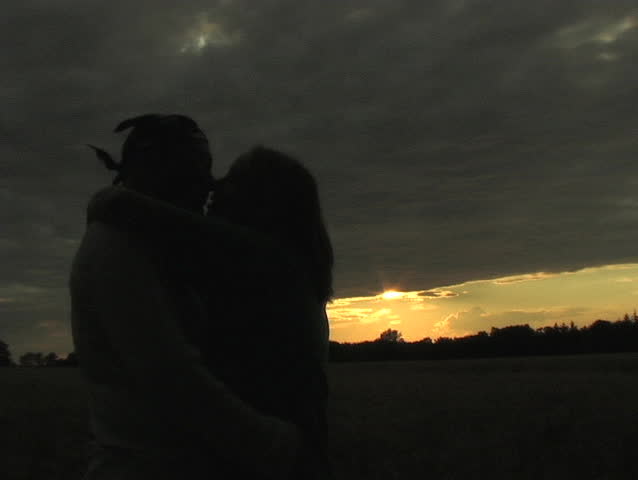A COUPLE KISSES AT SUNSET