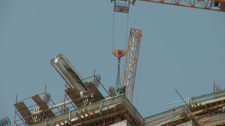 A rigger works atop of a new hi rise building site as a crane moves into