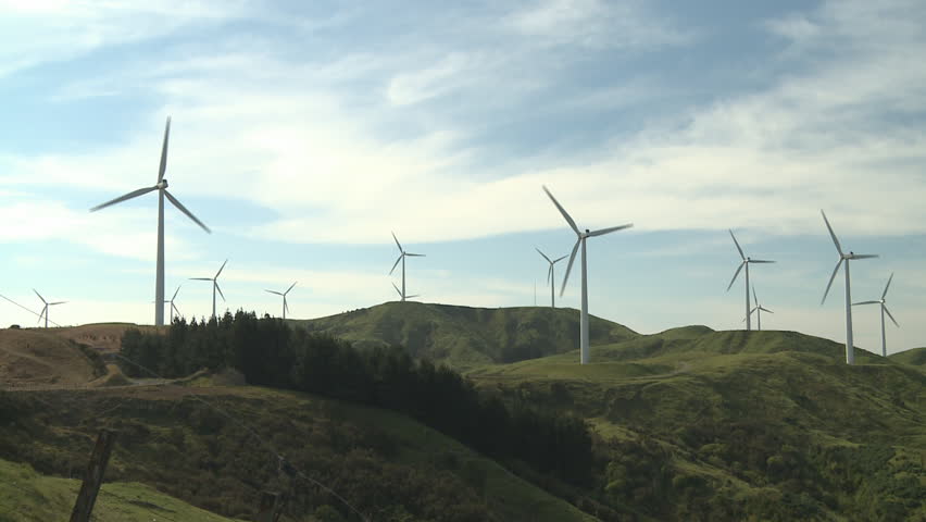 A row of wind turbines in a rugged farming country in New Zealand