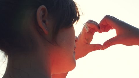 female hands making heart shape gesture holding sun flare: film stockowy