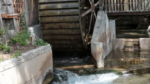 Old antique water wheel turning against a wood building. Water diverted from creek. Steel wheel and spokes. Turning from power of a small creek in central Utah. Used for a mill.