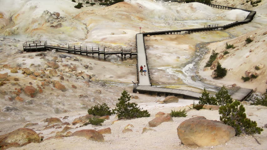 LASSEN VOLCANIC NATIONAL PARK, CALIFORNIA - July 20, 2013: Two people walking the boardwalk over the geothermal hot springs of Bumpass Hell in Lassen Volcanic National Park.